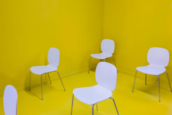 sala completamente gialla con sedie bianche